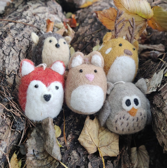 Håndlavet filtfigurer med ophængssnor. Dyr fra skoven dvs. en hare, en ræv, en ugle, en hjort og et pindsvin. Dyrerne sidder i skovbunden tæt på hinanden - ræven er rødlig og uglen er grå/hvid  og pindsvinet er brun etc.